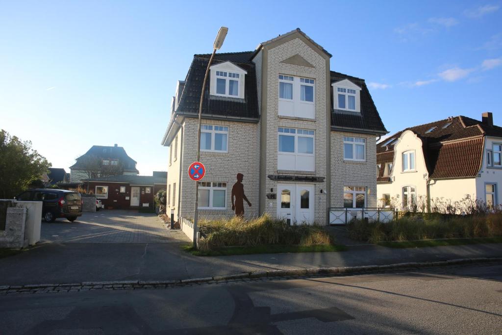 a man standing in front of a house on a street at Residenz Strandläufer in Wenningstedt