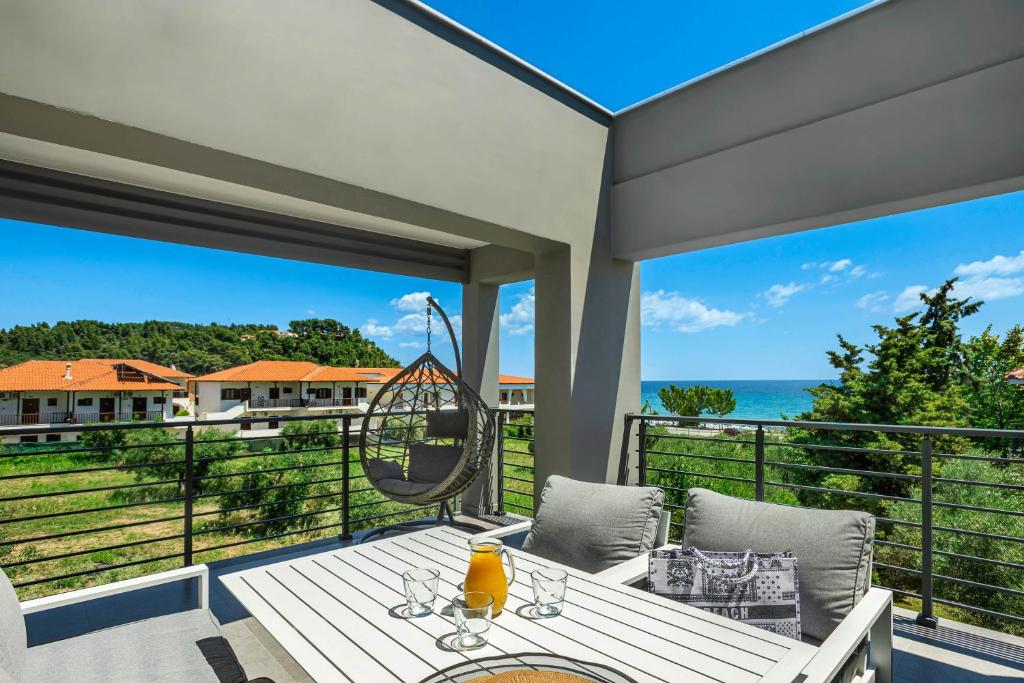 un patio con mesa y sillas y vistas al océano en NewStory Luxury Suites Possidi, en Possidi