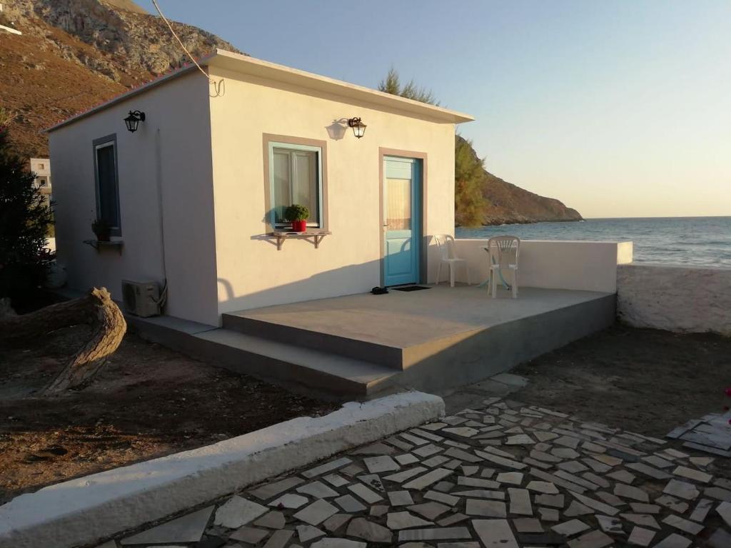 a small white house with a blue door next to the water at PARADISE ON THE KANTOUNI BEACH in Panormos Kalymnos
