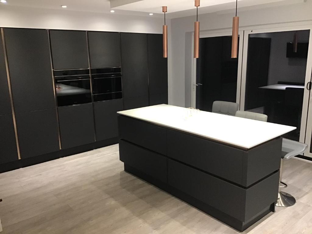 uma cozinha com armários pretos e um balcão branco em Redstone Rise Luxury house sleeps 7 em Birkenhead