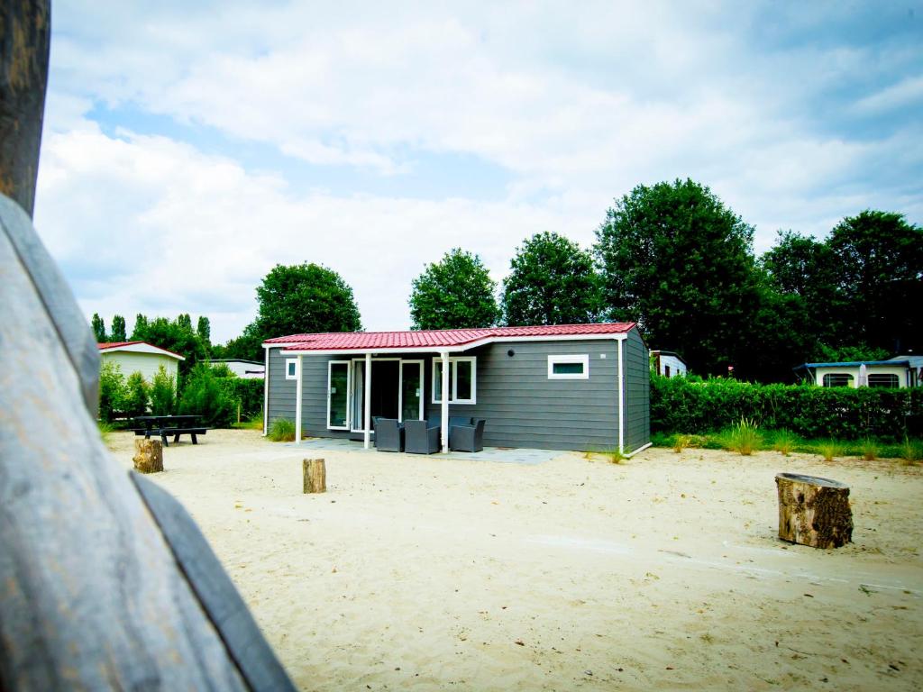 um pequeno barracão com um telhado vermelho na areia em Holiday Home Duinhoeve-1 by Interhome em Udenhout