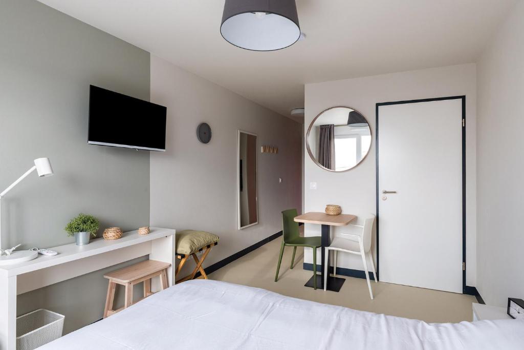 - une chambre avec un lit, une table et un miroir dans l'établissement Student Factory Le Havre Les Docks, au Havre