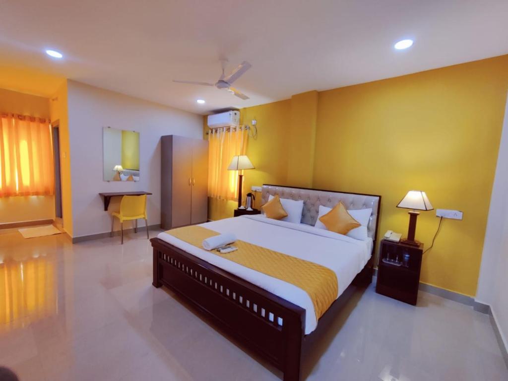 a bedroom with a large bed with yellow walls at Hotel Prime Classic in Shamshabad