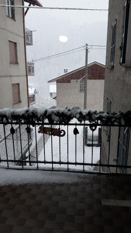 een hek bedekt met sneeuw met een auto die door een straat rijdt bij Casa Miky in Lanzada