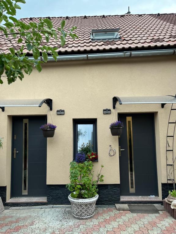 a house with black doors and flowers in pots at Privát u Zdenky in Tvrdošín