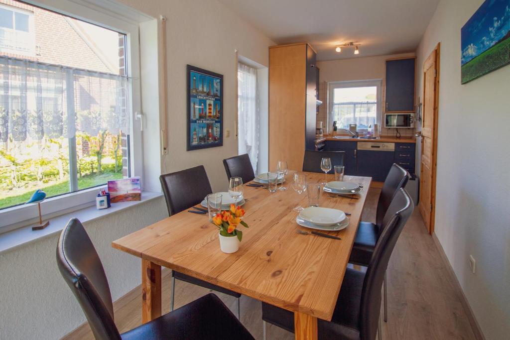 a dining room with a wooden table and chairs at Haus Leuchtturm - Flut in Krummhörn