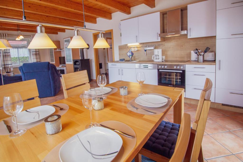 uma cozinha e sala de jantar com uma mesa de madeira com copos de vinho em Haus Merlin - Silbermöwe em Greetsiel