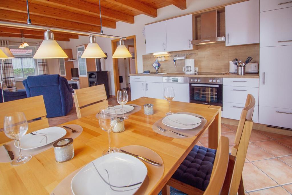 cocina y comedor con mesa de madera y copas de vino en Haus Merlin - Silbermöwe, en Greetsiel