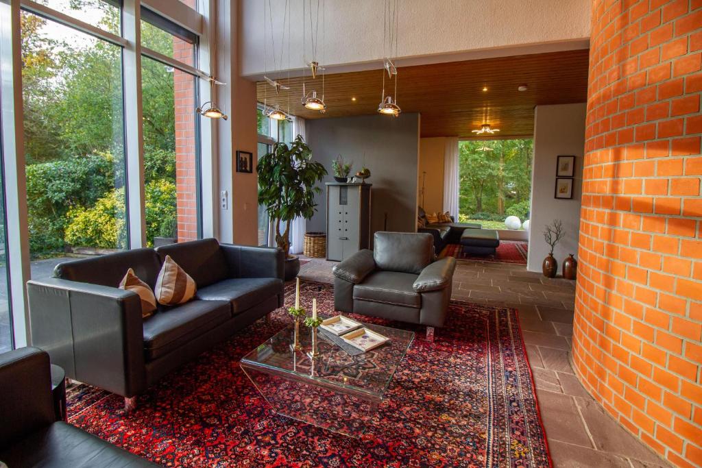 a living room with a couch and chairs and a brick wall at Architektenhaus am Pewsumer Tief in Krummhörn