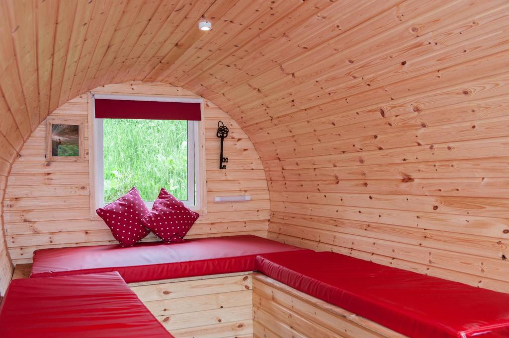 un banco rojo en una habitación de madera con ventana en BCC Lochness Glamping, en Bearnock