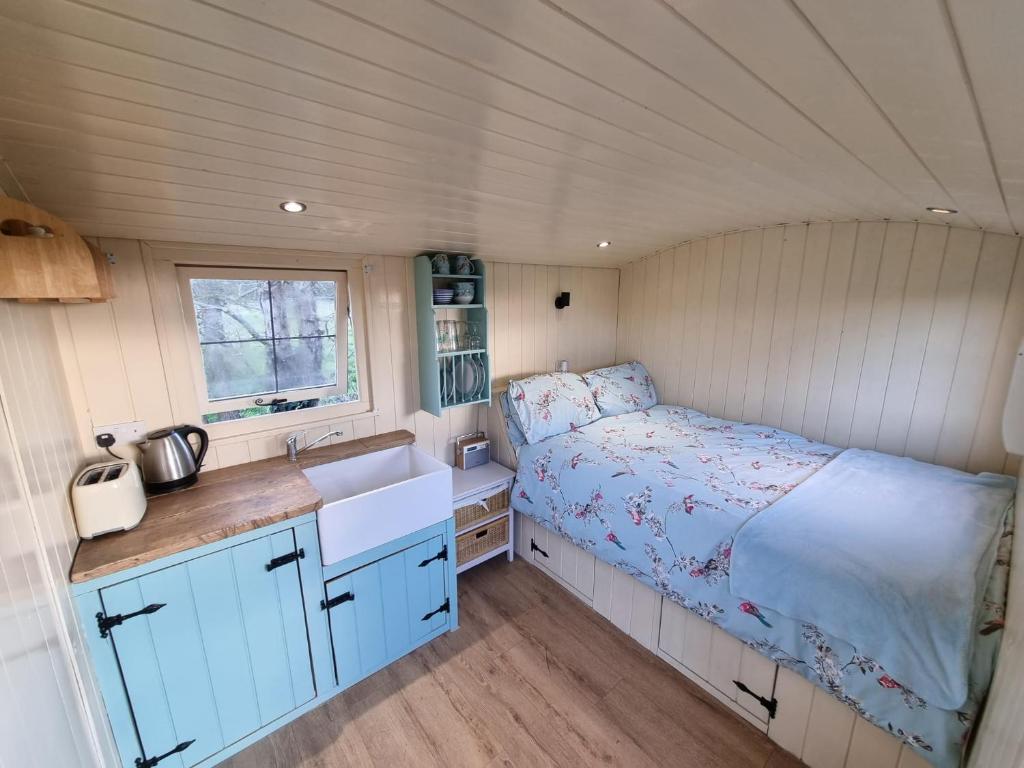 eine kleine Küche mit einem Bett in einem kleinen Zimmer in der Unterkunft Delilah the shepherd's hut in Sidlesham