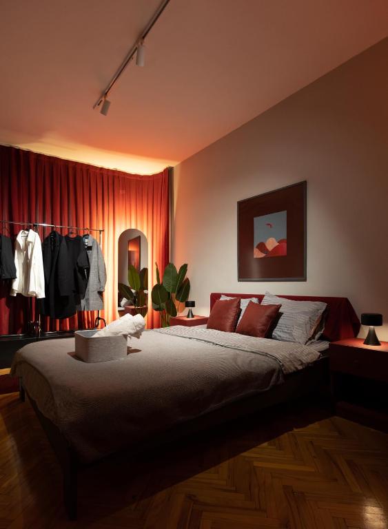 a bedroom with a large bed with red curtains at Etern Stays IEG - Maroon Apartment in Prishtinë