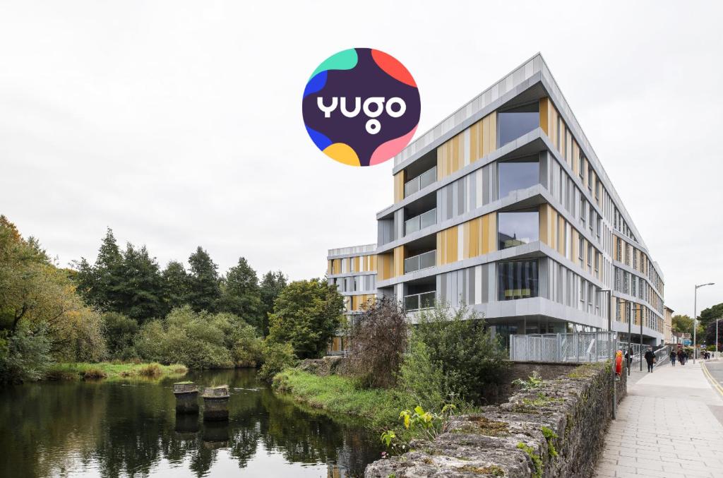 a building with a sign on it next to a river at Yugo Explore - Amnis House in Cork
