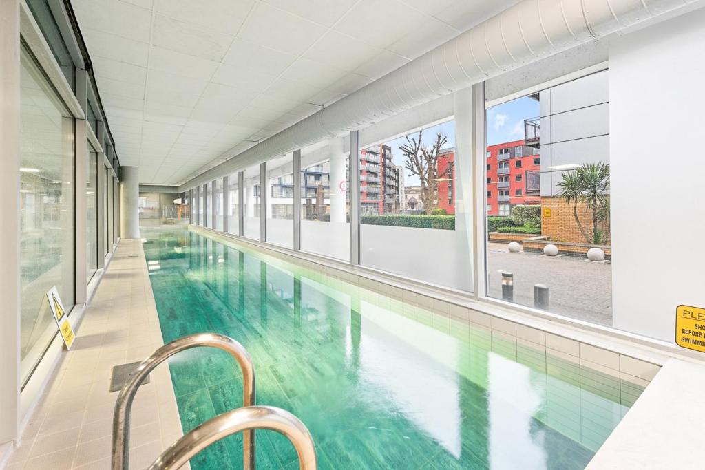 a swimming pool in a building with glass windows at Beautiful 1-Bed Apartment Central London in London