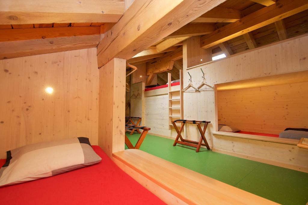 a small room with a bed in a wooden house at Hotel Bahnhof in Zermatt