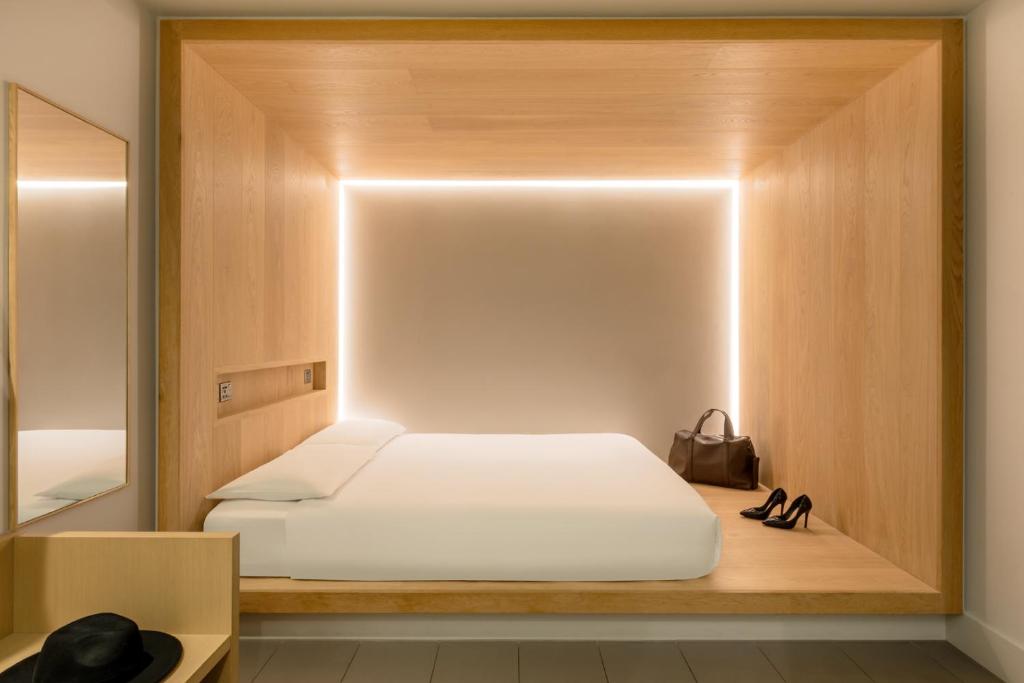 1 dormitorio con cama blanca y espejo en Zedwell Piccadilly Circus, en Londres