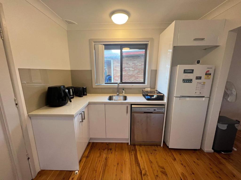 a small kitchen with a sink and a refrigerator at The Entrance & Shelly Beach Holiday House in Long Jetty