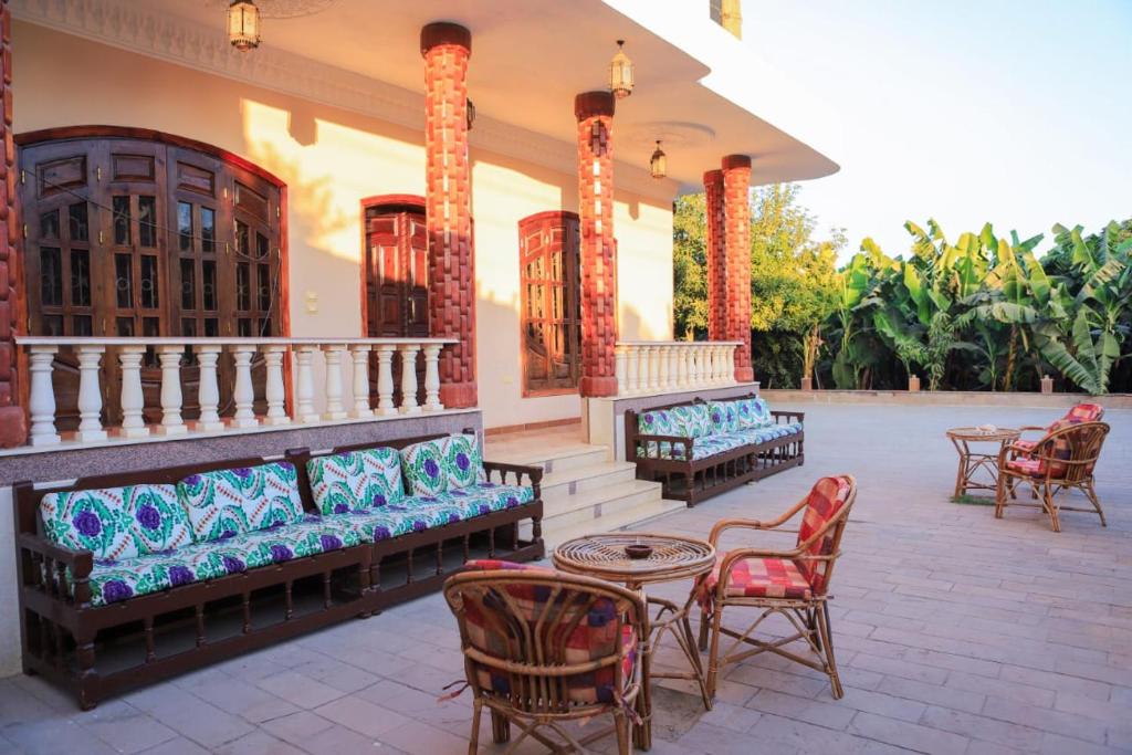 eine Terrasse mit Sofas, Stühlen und einem Tisch in der Unterkunft Tomorrow Land villa in Luxor