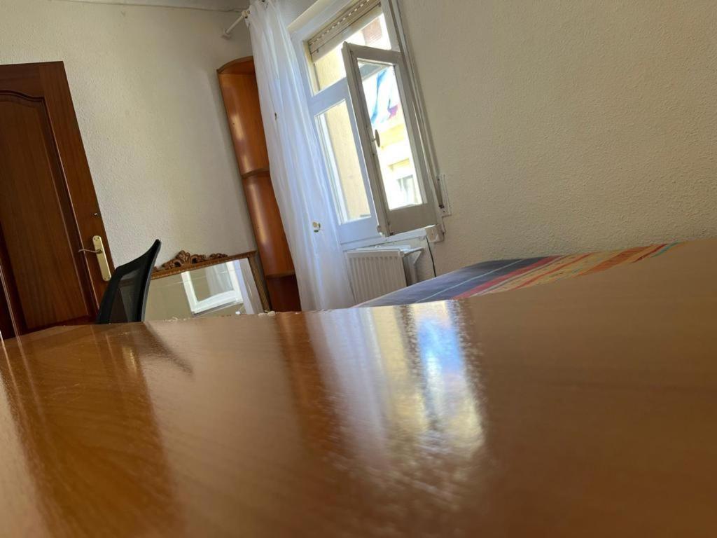 uma grande mesa de madeira num quarto com uma janela em Habitación cómoda a 10 minutos del centro em Pamplona