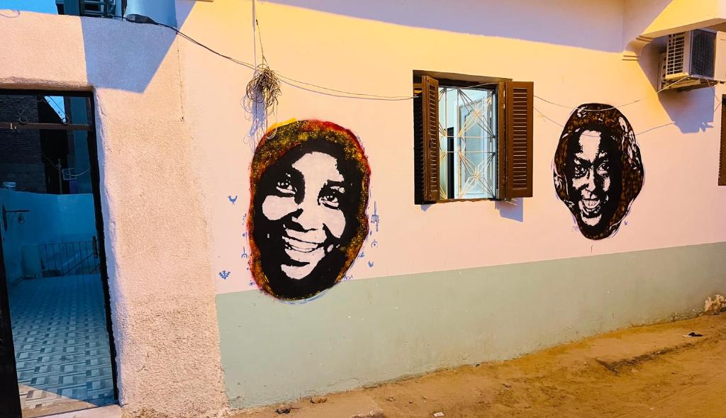 2 faces peintes sur le côté d'un bâtiment dans l'établissement Napata Guest House, à Assouan