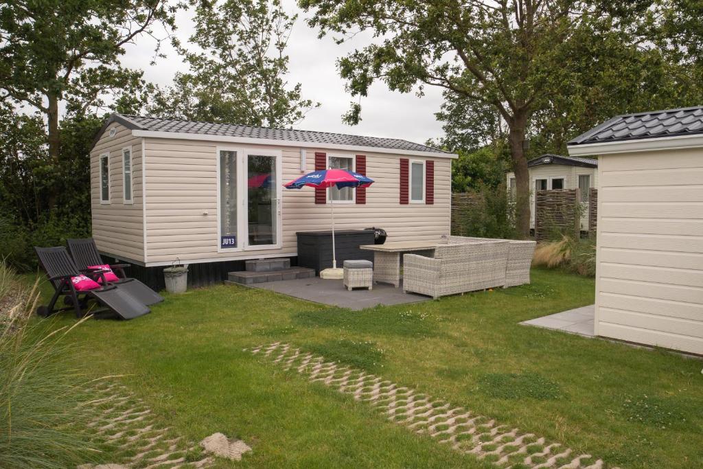 a tiny house with a table and an umbrella at Siblu Camping de Oase in Renesse
