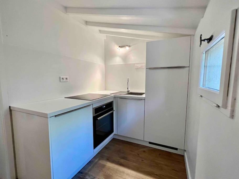 een witte keuken met een wastafel en een koelkast bij Jolie maison - Place des Lices à 350m in Saint-Tropez