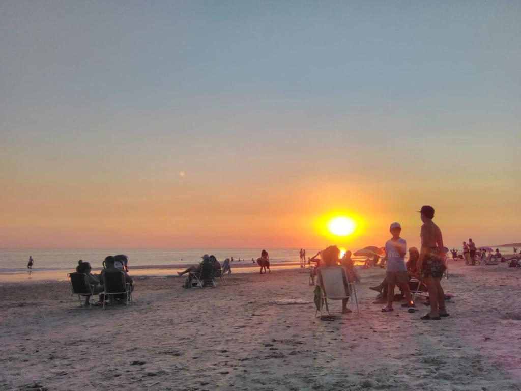 un grupo de personas en la playa mirando la puesta de sol en Delastres, en Cuchilla Alta