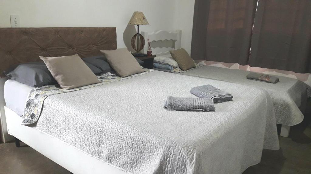 a large white bed with two towels on it at Chalé das Alamandas in Socorro