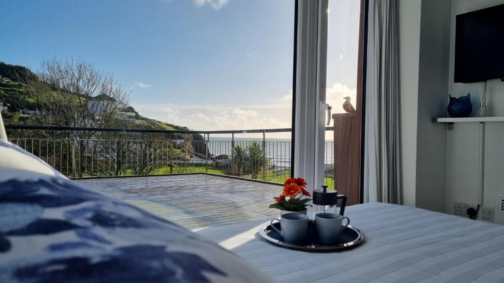 Cette chambre dispose d'une table et d'un balcon. dans l'établissement May View - Luxury Sea View Apartment - Millendreath, Looe, à Looe