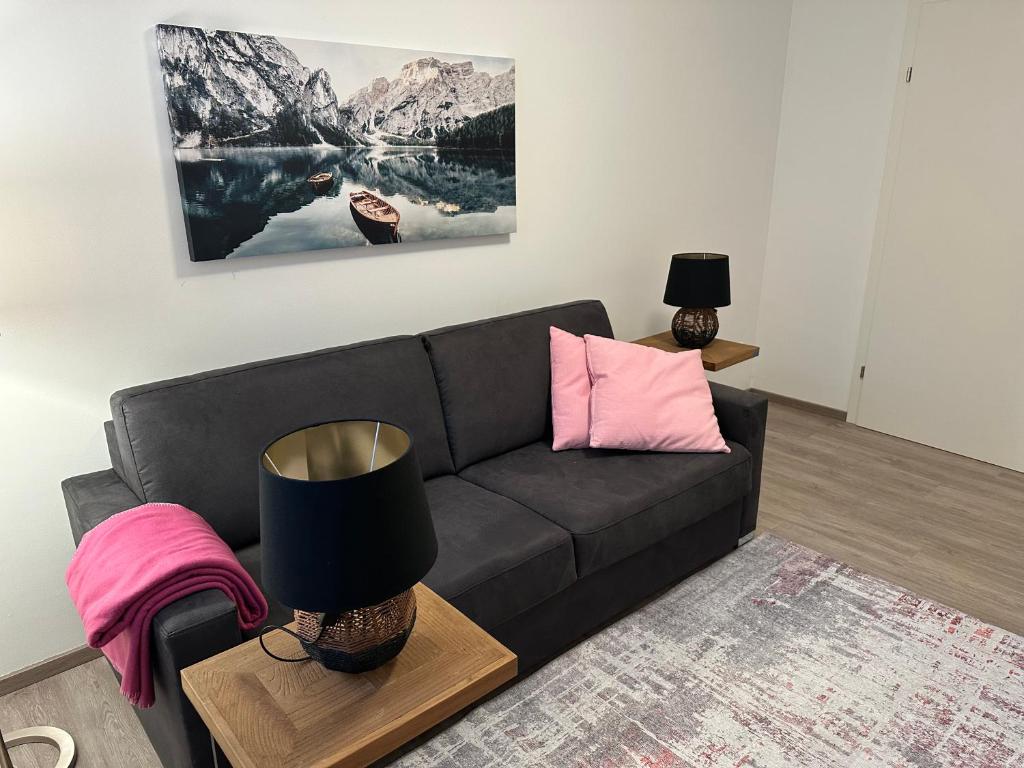 a living room with a black couch and pink pillows at Ferienwohnung Fischerweg in Bodensdorf