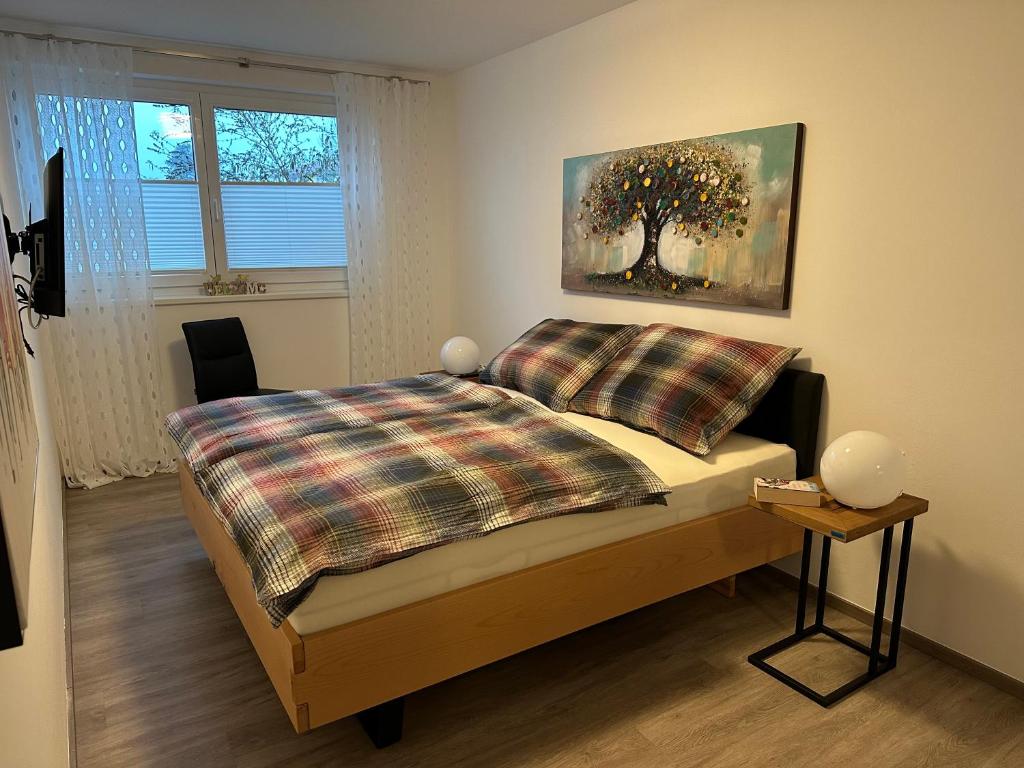 a bedroom with a bed with a tree painting on the wall at Ferienwohnung Fischerweg in Bodensdorf