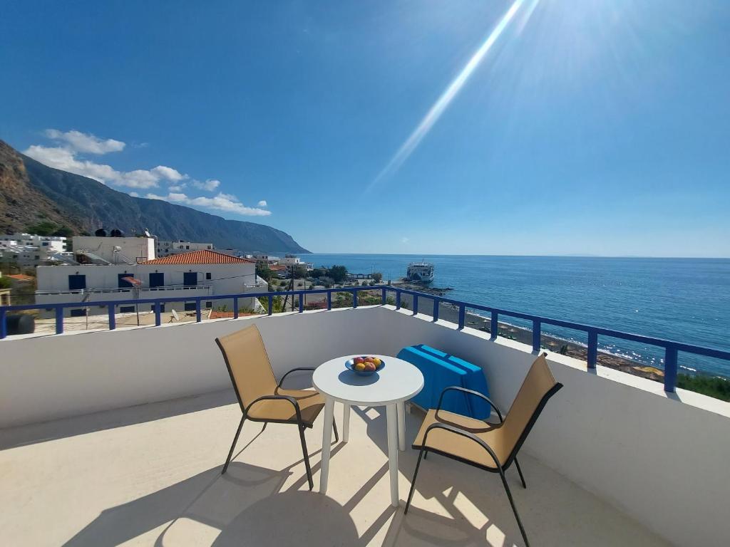 a balcony with a table and chairs and the ocean at Hotel Agia Roumeli by the SEA in Agia Roumeli