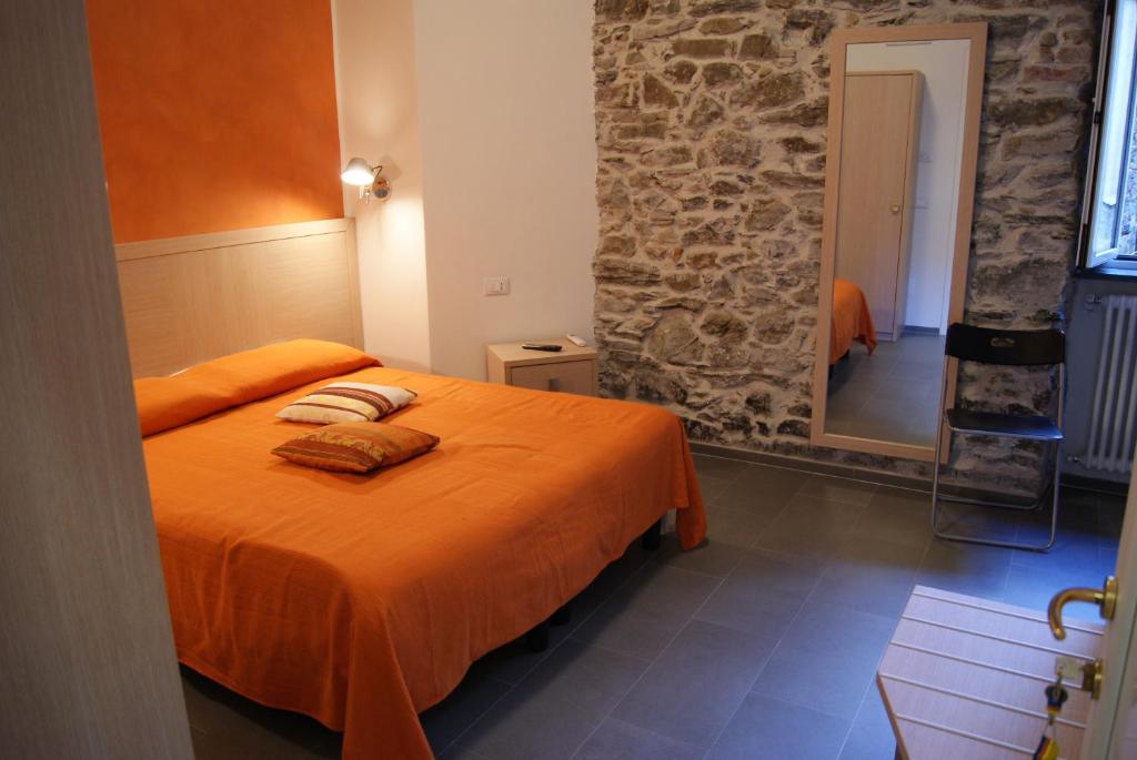 een slaapkamer met een bed met oranje lakens en een spiegel bij Hotel La Zorza in Riomaggiore