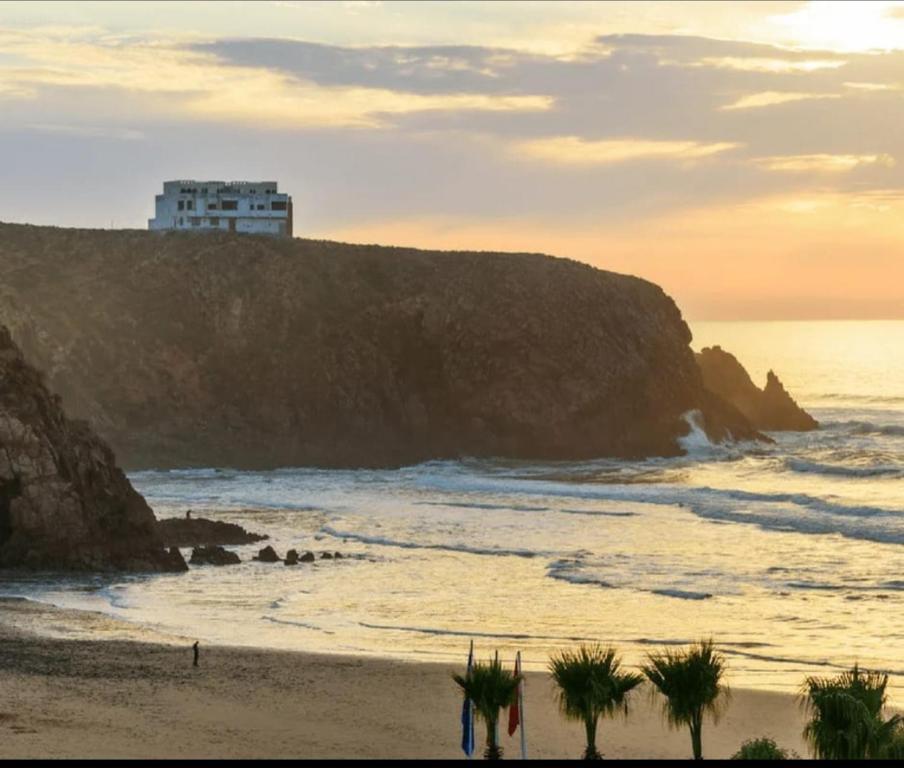 a beach with a building on top of a cliff at Dar diafa samira in Mirleft