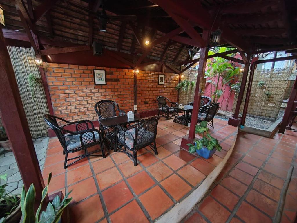 un patio con mesas y sillas y una pared de ladrillo en Soben Cafe Guesthouse & Restaurant en Siem Reap