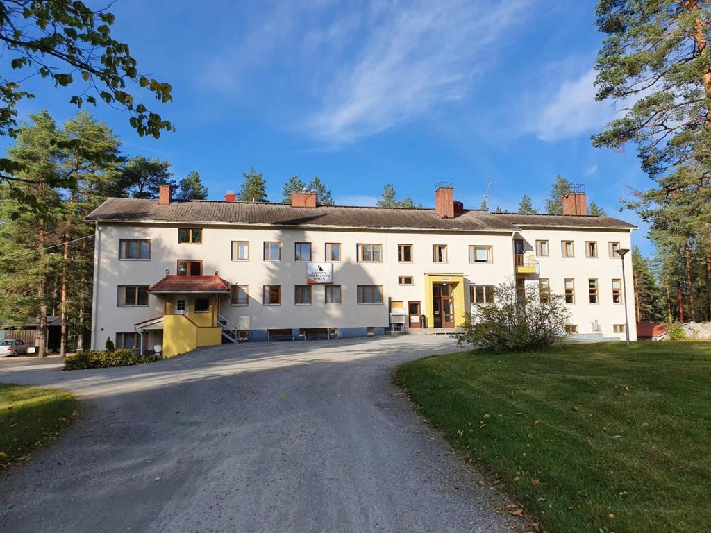 a large white house with a driveway at Hostelli Kotiranta in Lieksa