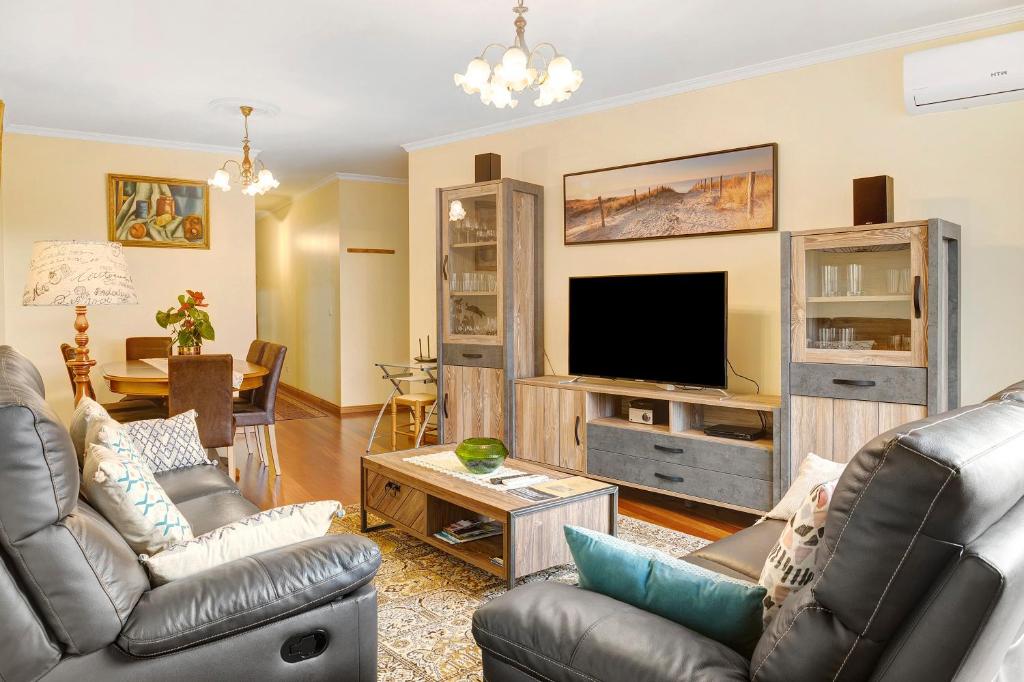 sala de estar con muebles de cuero y TV de pantalla plana en Palheiro Residence Vista Mar, en Funchal