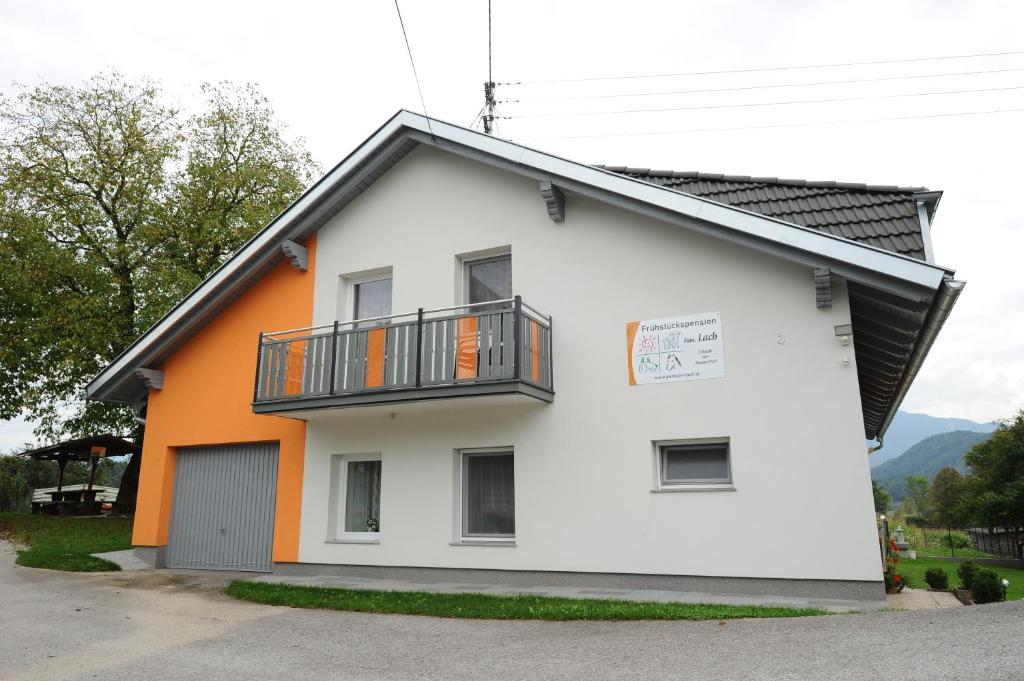 ein weißes und orangefarbenes Haus mit einem Balkon in der Unterkunft Frühstückspension Lach in Eberndorf