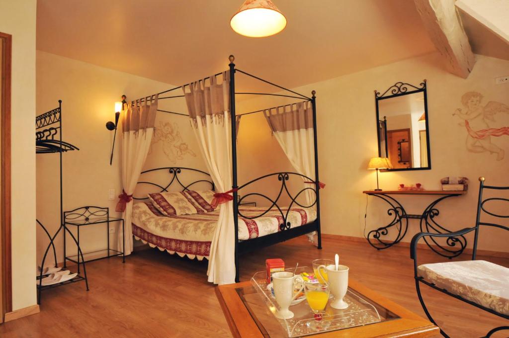 een slaapkamer met een hemelbed en een tafel met drankjes bij La p'tite Boulonne in Festigny