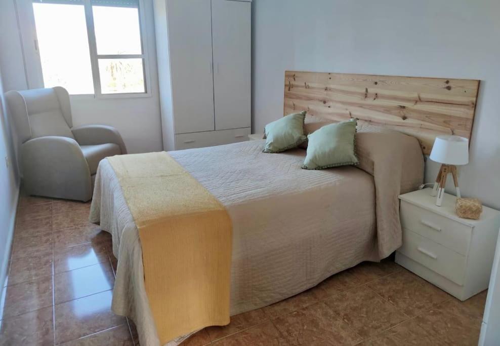 a bedroom with a large bed and a chair at Apartamento céntrico con vistas in Melilla