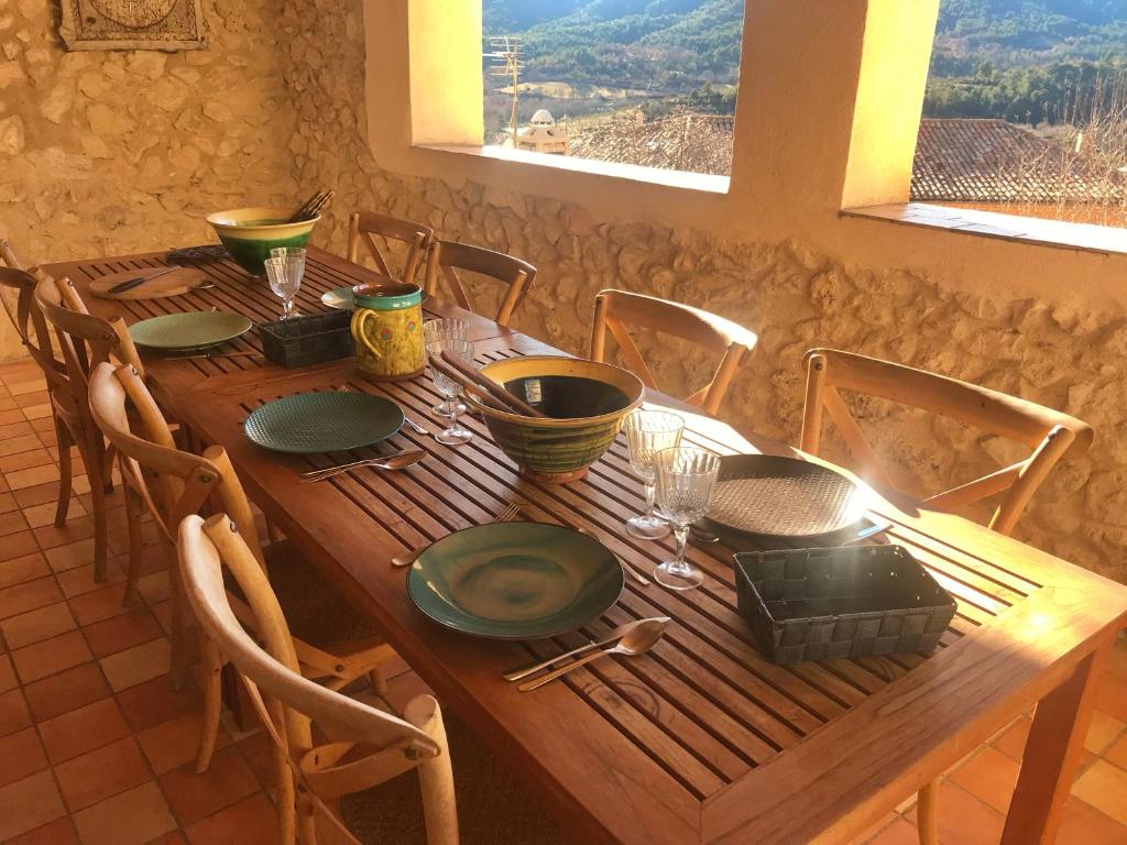 une table en bois avec des assiettes et des bols dans l'établissement Chambres d' hôtes l'Escalo à Moutiers-Ste-Marie (04360), à Moustiers-Sainte-Marie