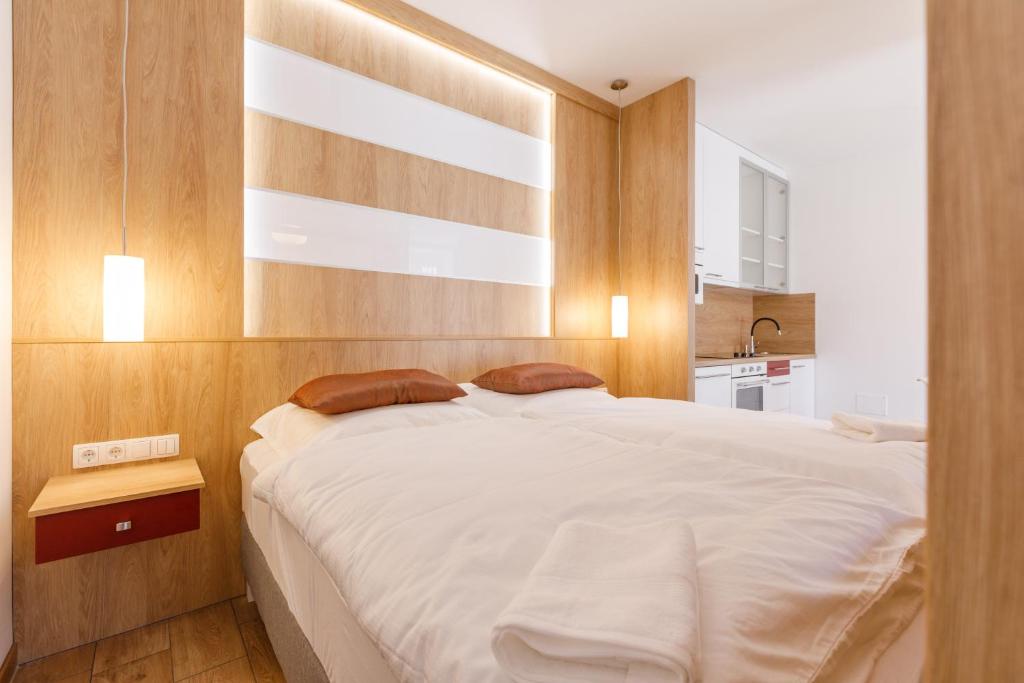 a bedroom with a large white bed with wooden walls at La Bella Centrum apartmanok Piros/Sárga in Hévíz