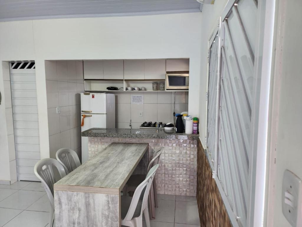 una pequeña cocina con mesa de madera y sillas en BARREIRINHAS CHALÉ 12 PORTO DOS LENÇÓIS en Barreirinhas