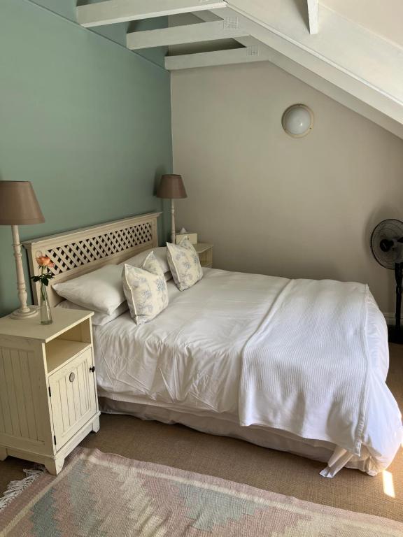 a bed with white sheets and pillows in a bedroom at Constantia cottage- Warblers Nest in Cape Town