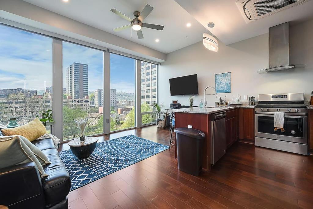 a living room with a kitchen and a large window at HostWise Stays - The Washington at Chatham - Free Garage Parking across from PPG Arena in Pittsburgh