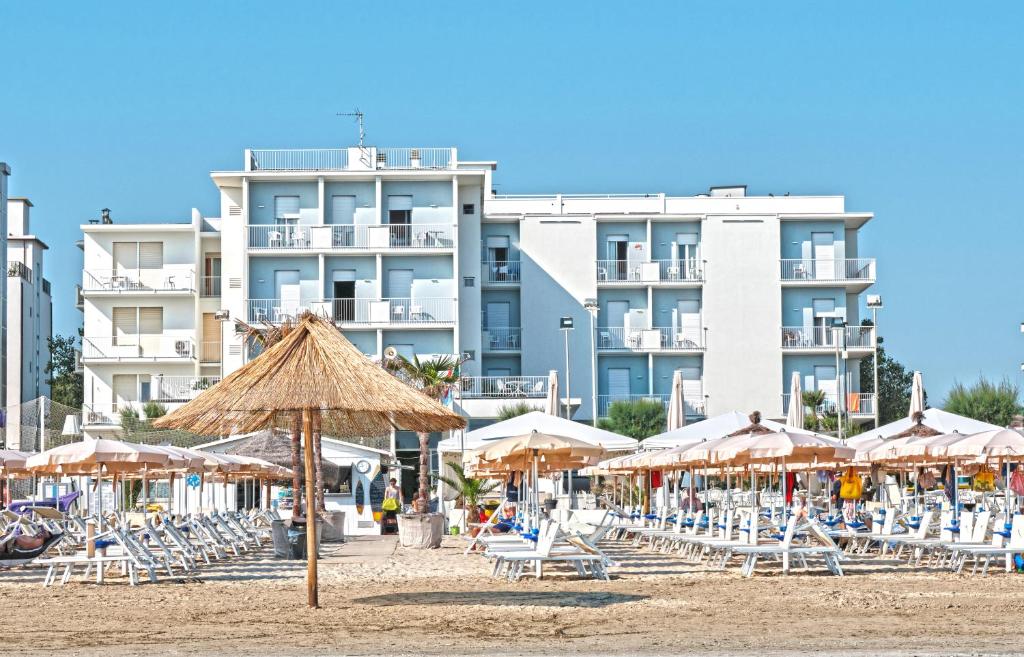 a beach with chairs and umbrellas and a building at Hotel Continental in Senigallia