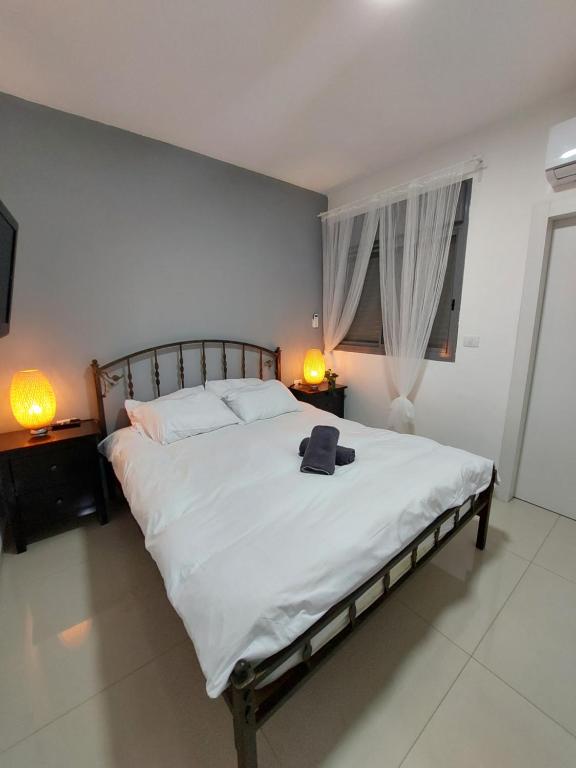 ティベリアにあるאירוח ברמה אחרתのベッドルーム(白い大型ベッド、ランプ2つ付)