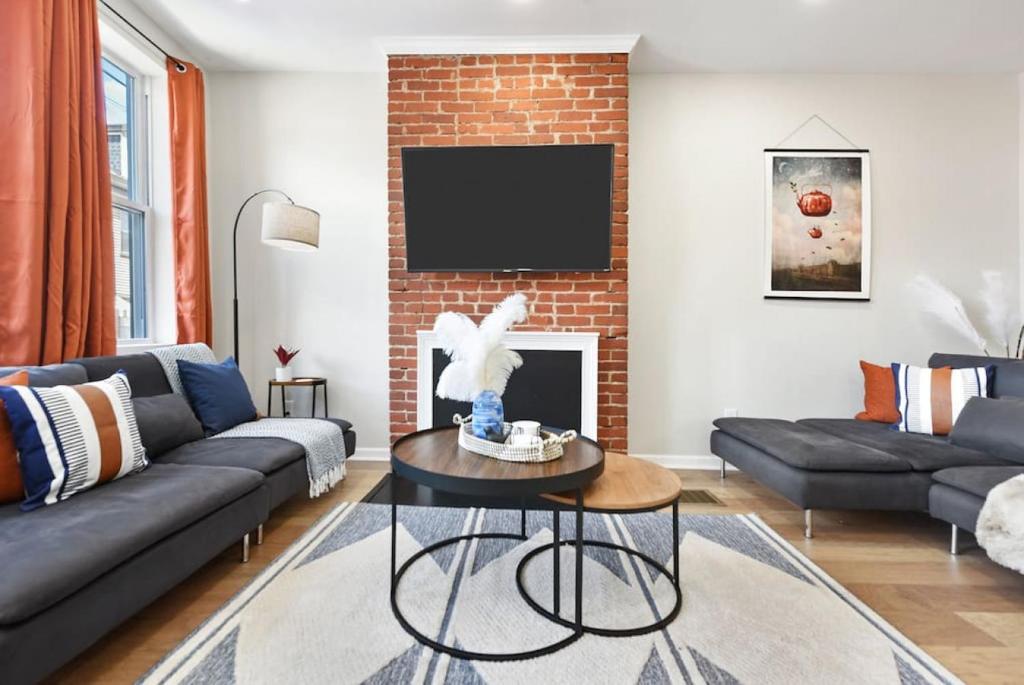 a living room with a couch and a brick wall at HostWise Stays - The Peralta - Brand New, Great Kitchen, Theater Room in Pittsburgh