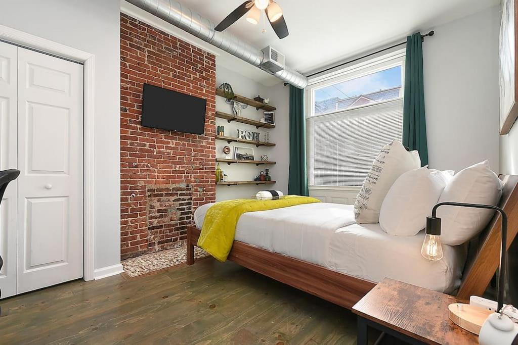 1 dormitorio con cama y pared de ladrillo en HostWise Stays - The James Apt 1 - Patio, Free Street Parking, en Pittsburgh