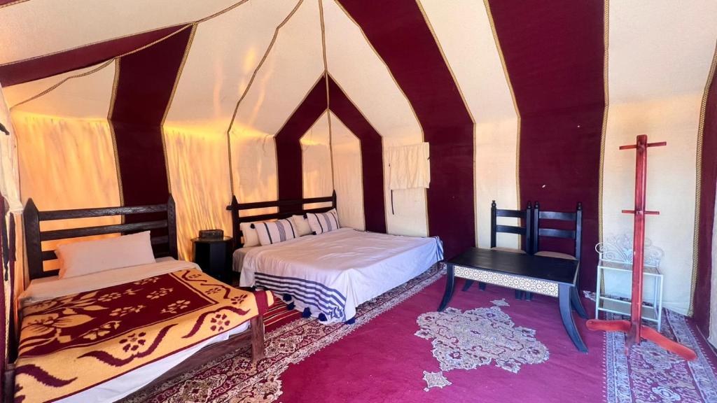 Habitación con 2 camas y una cruz en la pared. en Sahara Luxury Camp, en Zagora